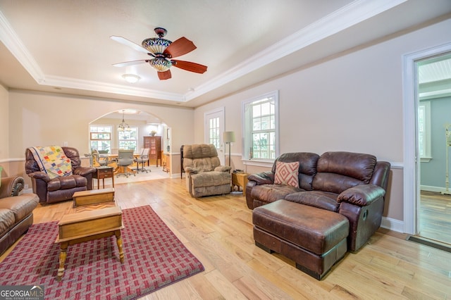 living room with ceiling fan, light hardwood / wood-style floors, a raised ceiling, and crown molding