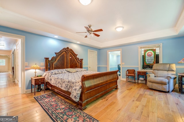 bedroom with ceiling fan, crown molding, light hardwood / wood-style flooring, and a tray ceiling