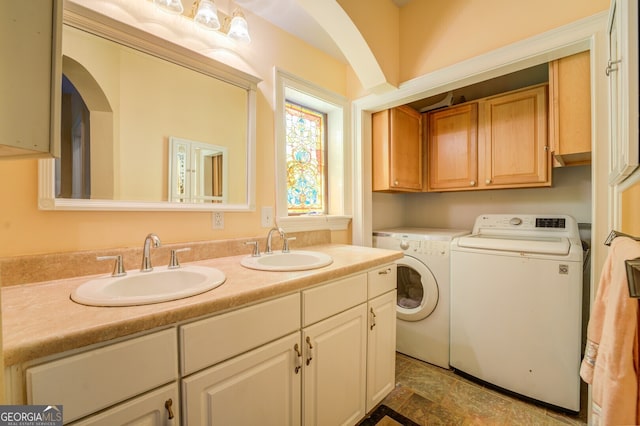 laundry area featuring dark tile patterned floors, washing machine and dryer, sink, and cabinets