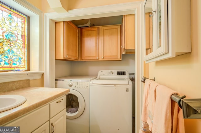 washroom with sink, washing machine and dryer, and cabinets