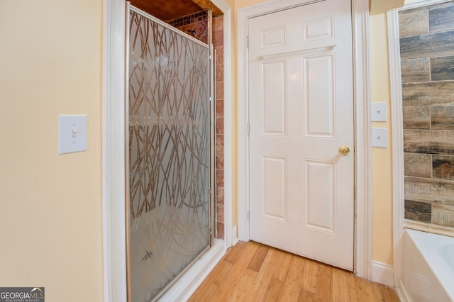 bathroom with hardwood / wood-style floors and independent shower and bath