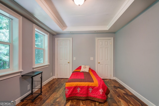 bedroom with ornamental molding, dark hardwood / wood-style flooring, and a tray ceiling