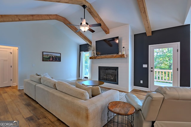 living room featuring ceiling fan, a large fireplace, lofted ceiling with beams, and hardwood / wood-style floors