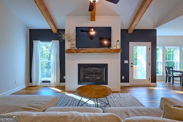 living room featuring ceiling fan, a large fireplace, vaulted ceiling with beams, and hardwood / wood-style floors