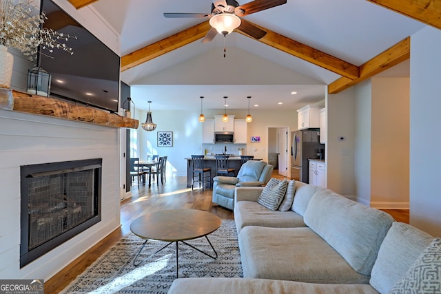 living room with beam ceiling, ceiling fan, light hardwood / wood-style floors, and high vaulted ceiling