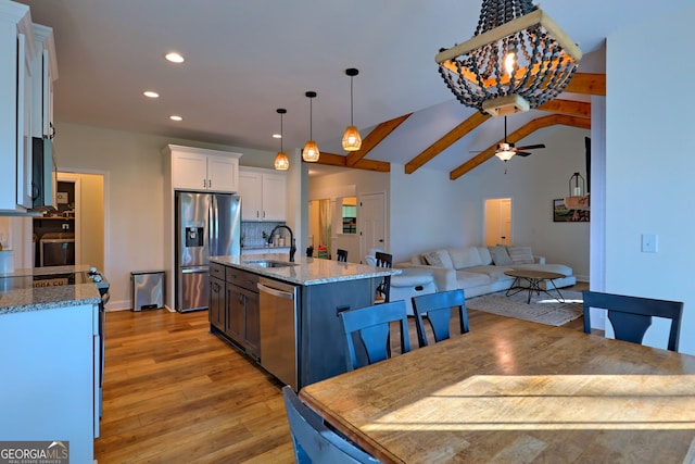 kitchen with appliances with stainless steel finishes, sink, hanging light fixtures, white cabinets, and an island with sink