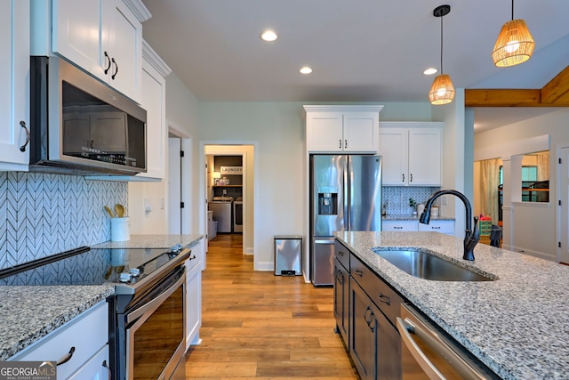 kitchen featuring appliances with stainless steel finishes, sink, white cabinetry, and light stone countertops