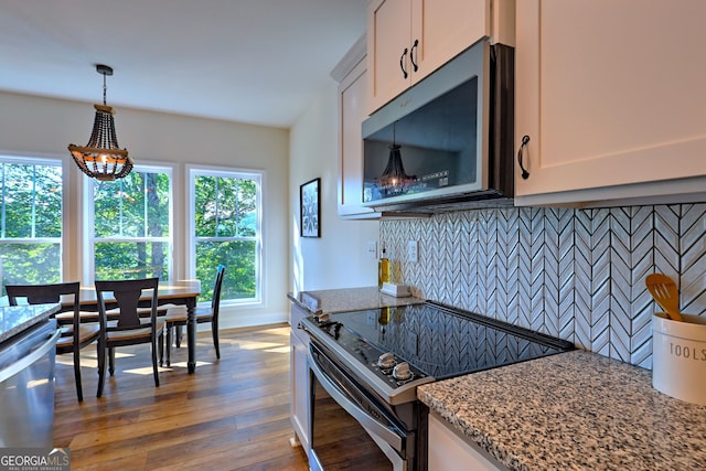 kitchen featuring white cabinets, light stone countertops, stainless steel appliances, and decorative backsplash