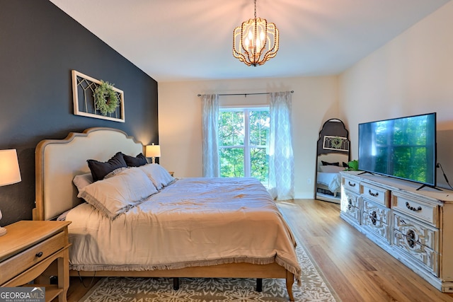 bedroom with light wood-type flooring and a notable chandelier