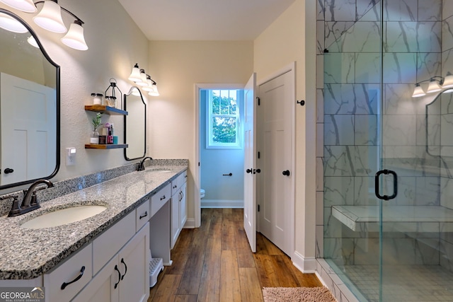 bathroom with wood-type flooring, vanity, a shower with door, and toilet