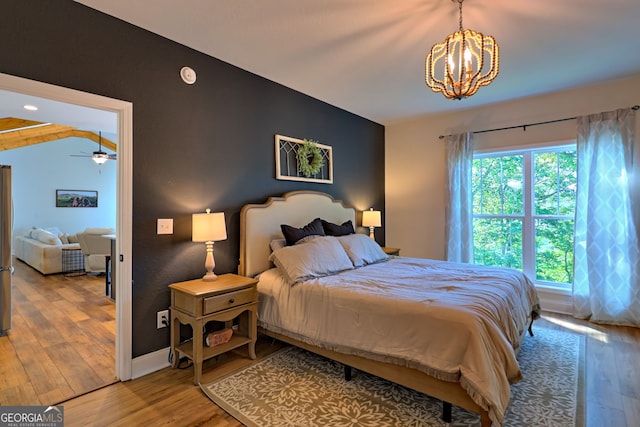 bedroom with vaulted ceiling, hardwood / wood-style floors, and an inviting chandelier