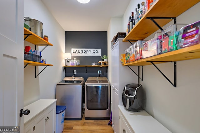 laundry area featuring washing machine and dryer, light hardwood / wood-style floors, and cabinets