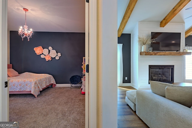 bedroom with hardwood / wood-style floors, an inviting chandelier, a large fireplace, and beam ceiling