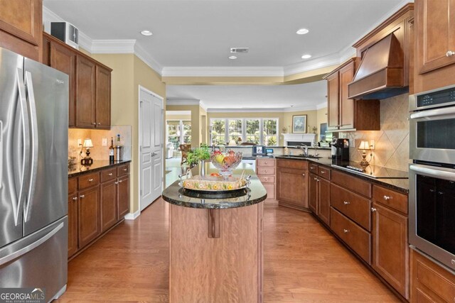 kitchen with a kitchen island, backsplash, light wood-type flooring, and stainless steel appliances