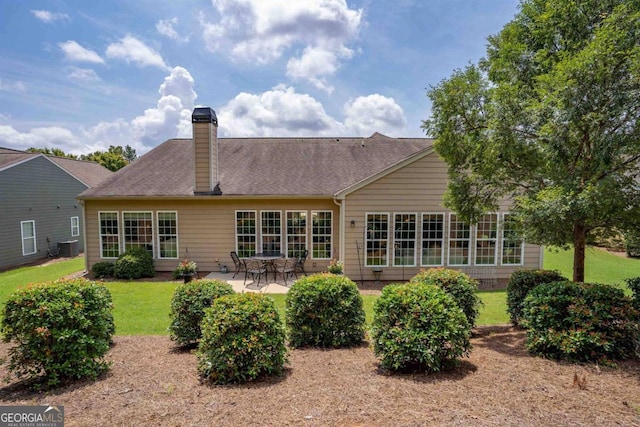 back of property with a chimney, a patio area, and a lawn