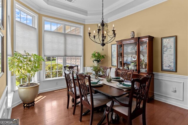 dining room with dark hardwood / wood-style floors, crown molding, a notable chandelier, and a raised ceiling