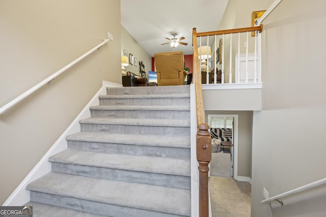 stairs with a high ceiling, ceiling fan, and carpet