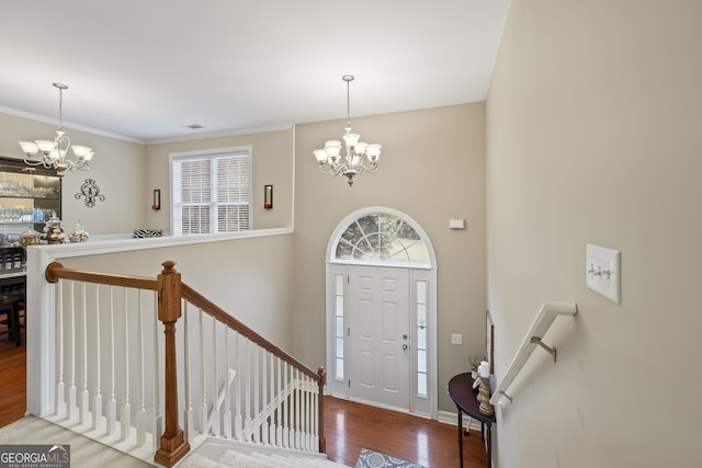 foyer featuring hardwood / wood-style floors, ornamental molding, and a chandelier