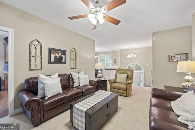 living room featuring light carpet and ceiling fan with notable chandelier