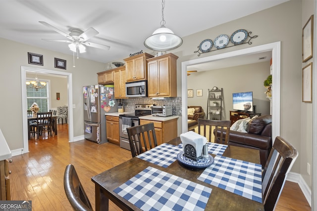 dining room with light wood-type flooring and ceiling fan with notable chandelier