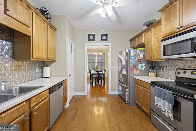 kitchen featuring ceiling fan with notable chandelier, backsplash, appliances with stainless steel finishes, and light hardwood / wood-style floors