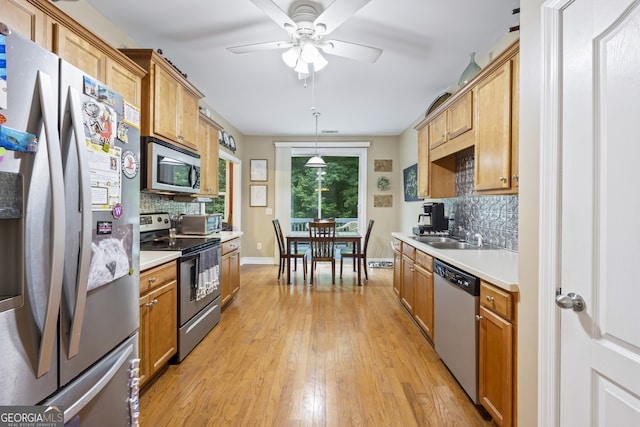 kitchen featuring appliances with stainless steel finishes, light hardwood / wood-style flooring, tasteful backsplash, ceiling fan, and hanging light fixtures