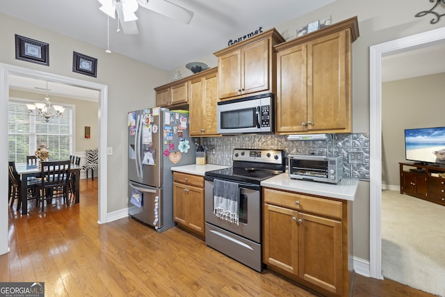 kitchen featuring ceiling fan with notable chandelier, backsplash, stainless steel appliances, and light colored carpet