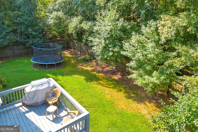 view of yard with a trampoline and a wooden deck