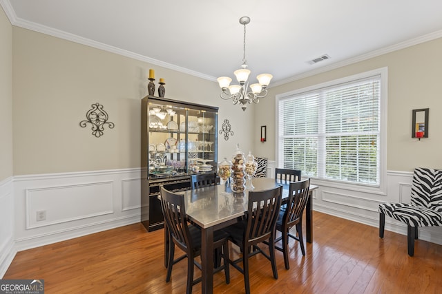 dining area with a notable chandelier, crown molding, and hardwood / wood-style floors