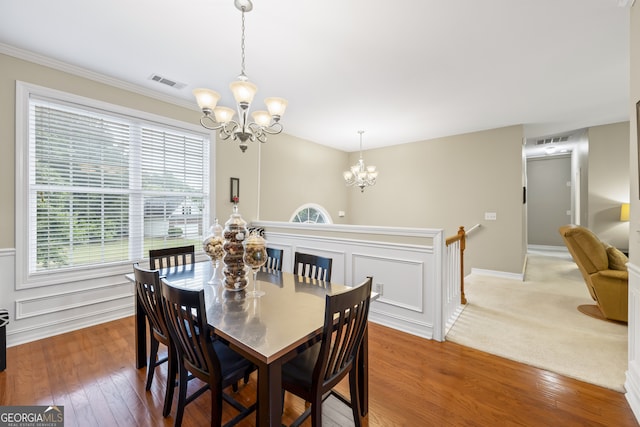 carpeted dining space with a notable chandelier and crown molding