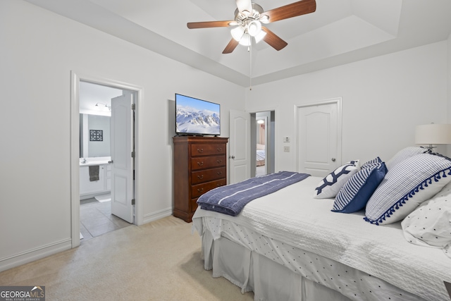 carpeted bedroom featuring ceiling fan, a raised ceiling, and ensuite bath