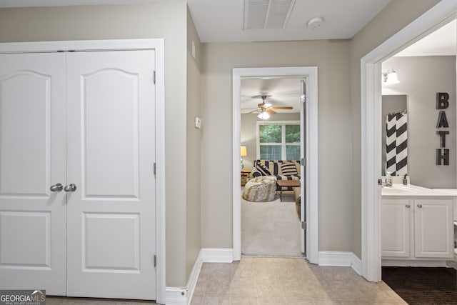 hallway with light colored carpet and sink