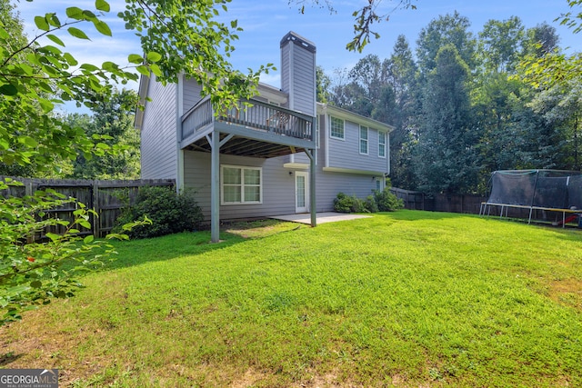 rear view of property with a trampoline, a patio area, and a yard