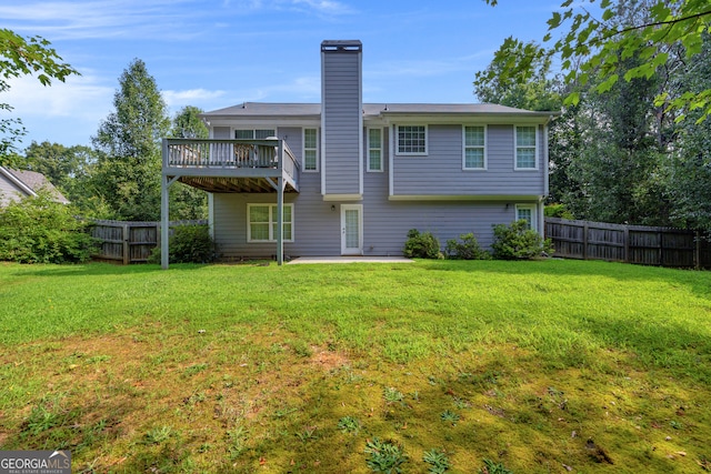 back of property featuring a wooden deck and a lawn