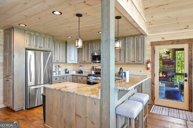 kitchen featuring decorative light fixtures, dark wood-type flooring, wood ceiling, and stainless steel appliances