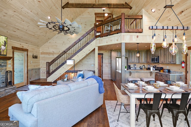 living room with high vaulted ceiling, wood walls, and hardwood / wood-style floors