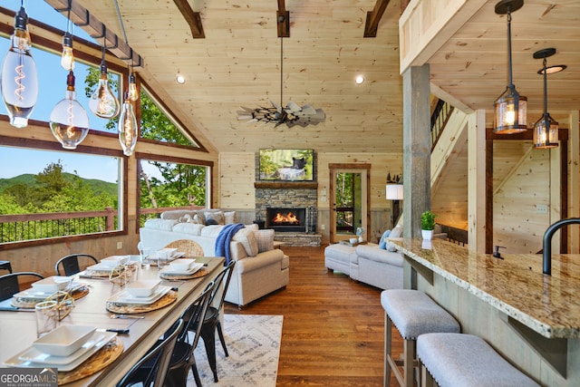 dining room with wood walls, hardwood / wood-style floors, high vaulted ceiling, a fireplace, and wooden ceiling