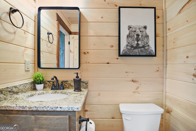 bathroom with wood walls, vanity, and toilet