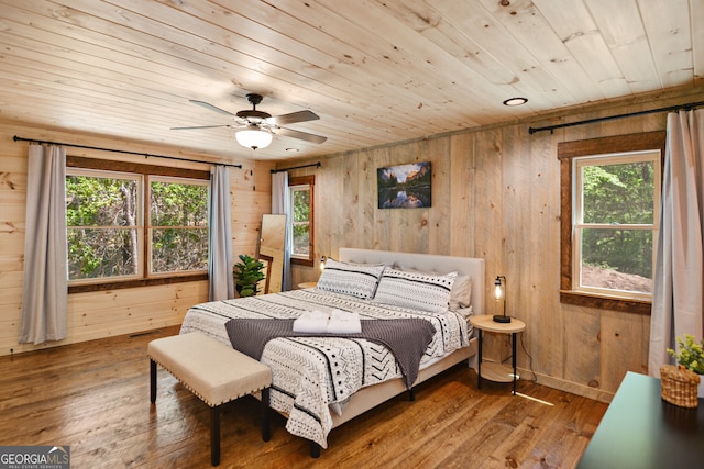 bedroom featuring wooden walls, multiple windows, and wood-type flooring