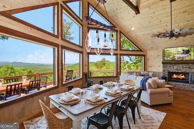 dining area featuring a fireplace, high vaulted ceiling, dark hardwood / wood-style flooring, and wood walls