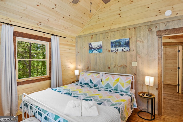 bedroom featuring wood-type flooring, wooden ceiling, vaulted ceiling, wooden walls, and ceiling fan