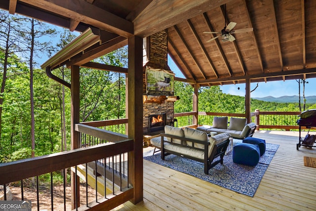 wooden deck featuring a mountain view, ceiling fan, and an outdoor living space with a fireplace