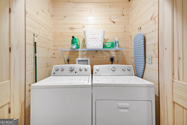 laundry area with wood walls and washer and clothes dryer