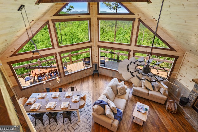 living room with wood walls, plenty of natural light, and high vaulted ceiling