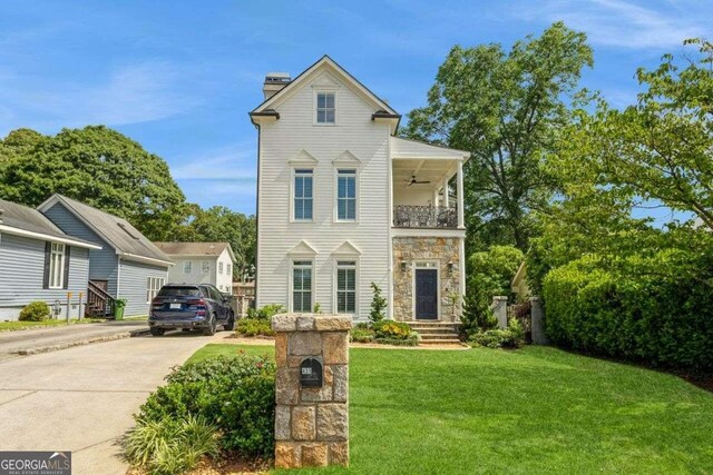 view of front of house featuring a balcony, ceiling fan, and a front lawn