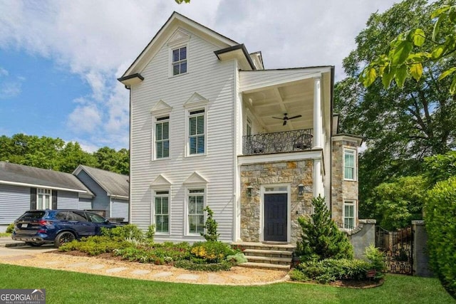 view of front of property featuring ceiling fan, a front lawn, and a balcony