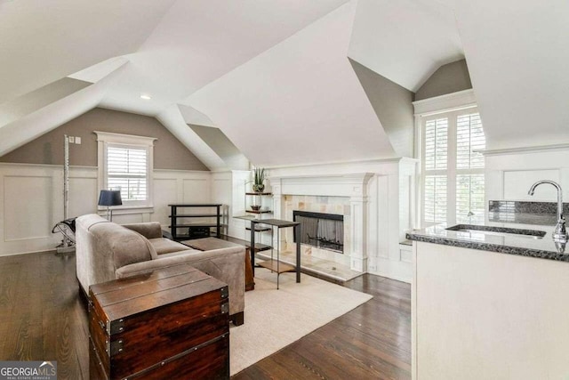 living room featuring sink, vaulted ceiling, dark hardwood / wood-style flooring, and a fireplace