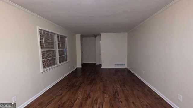 empty room with ornamental molding and dark hardwood / wood-style flooring