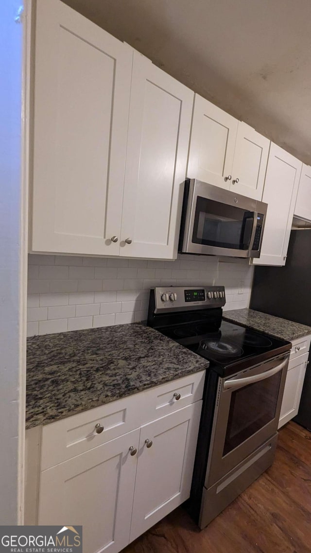 kitchen featuring dark stone counters, backsplash, dark hardwood / wood-style flooring, appliances with stainless steel finishes, and white cabinetry