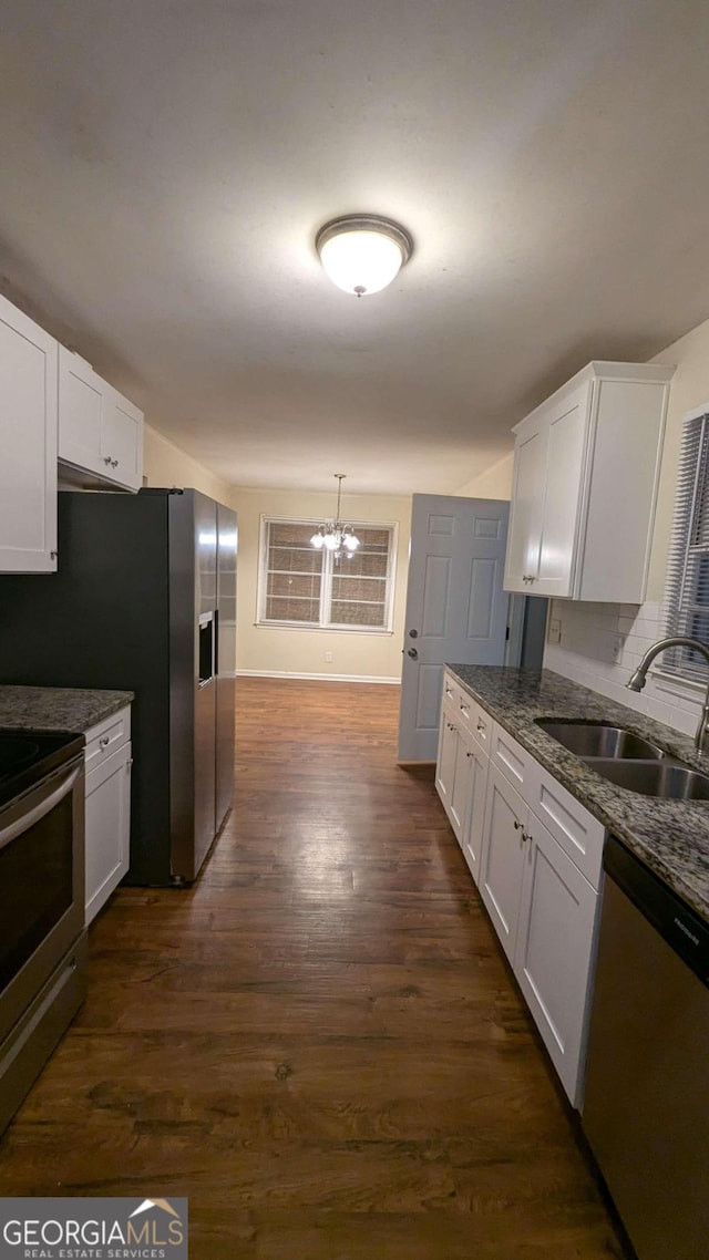 kitchen featuring appliances with stainless steel finishes, white cabinetry, an inviting chandelier, sink, and dark wood-type flooring